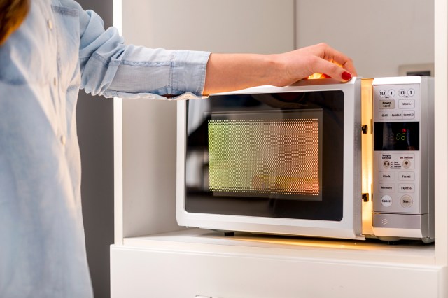 An image of a woman opening a microwave
