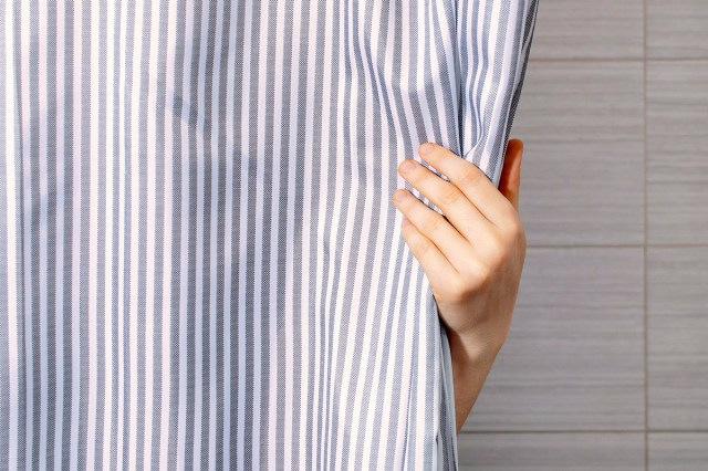 An image of a hand holding a striped shower curtain