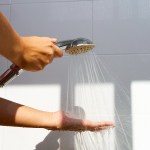 A person sprays water from a shower attachment over their hand