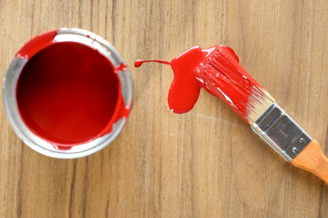 An image of a can of red paint and a paint brush with red paint on it
