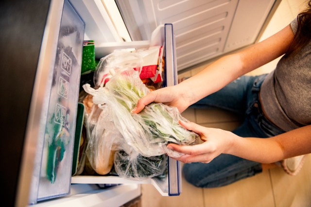 An image of a woman taking food out of the freezer