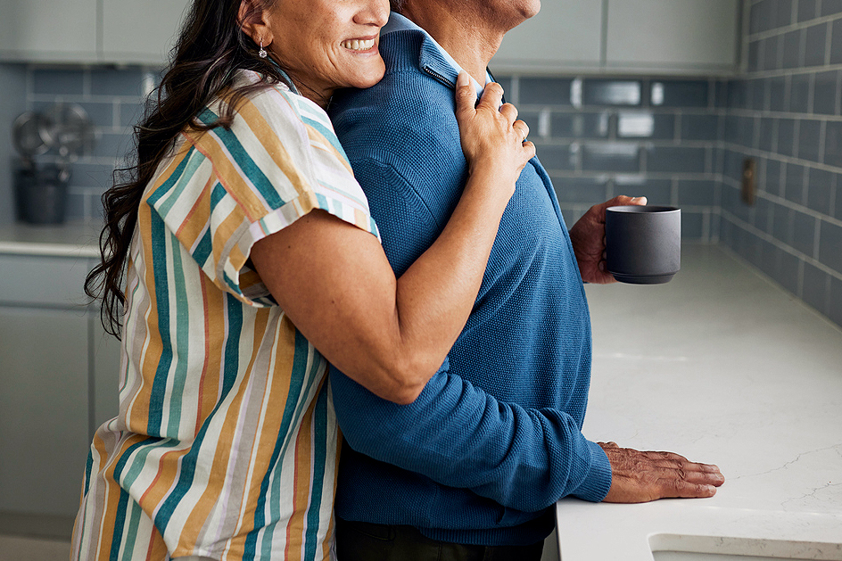 An image of a woman embracing a man in a kitchen
