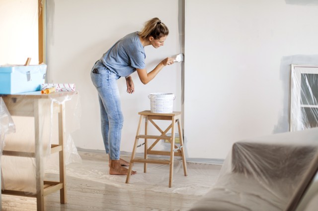 An image of a woman painting a room with white paint