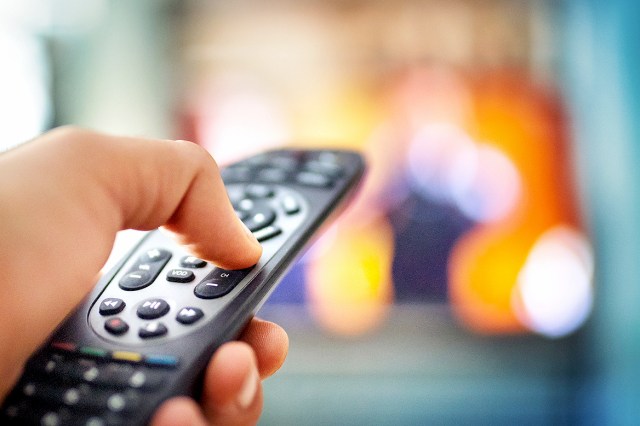 An image of a hand holding a remote control