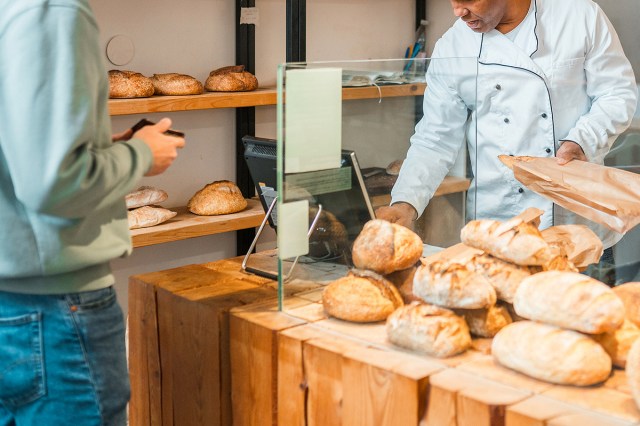 An image of a man buying a loaf of bread at a bakery
