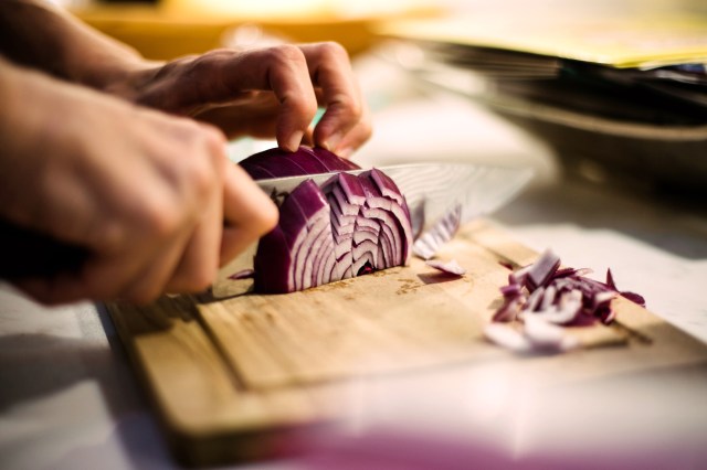 An image of a person chopping a red onion
