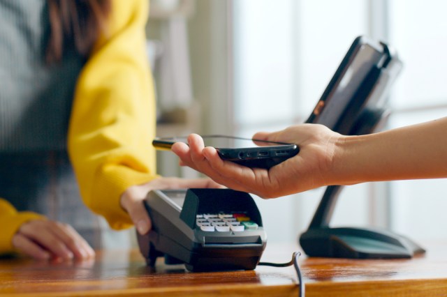 An image of a customer tapping their phone on a credit card machine