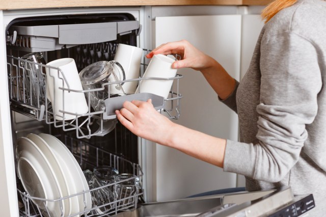 An image of woman putting a cup in the dishwasher