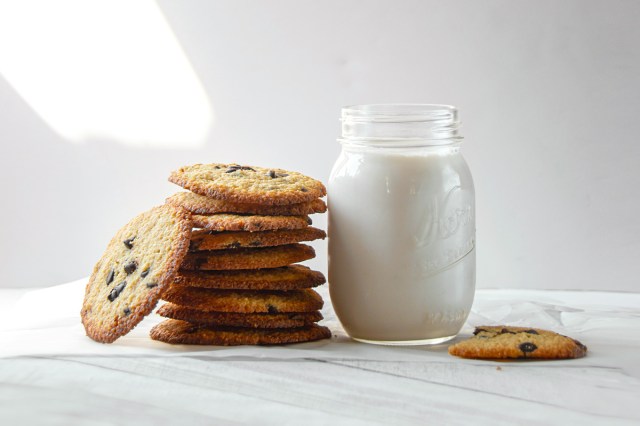 An image of a stack of chocolate chip cookies next to a jar of milk