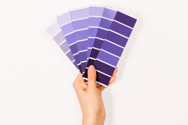 An image of a hand holding purple paint swatches