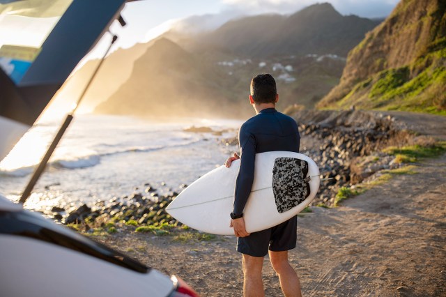 An image of a man holding a surfboard by the ocean