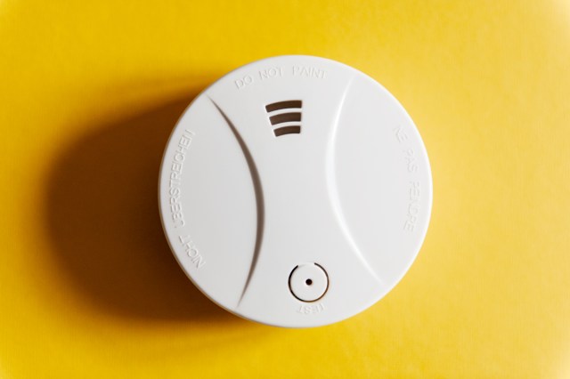 An image of a white smoke detector against a yellow background