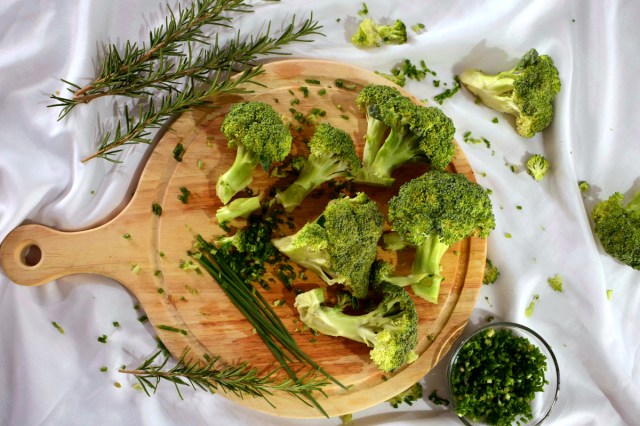 An image of broccoli on a wooden cutting board