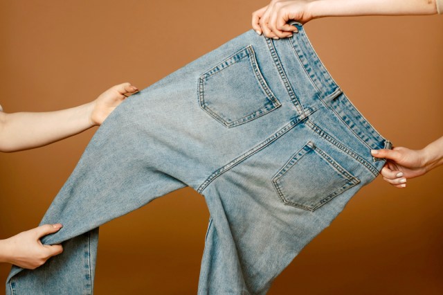 An image of two people holding a pair of blue jeans