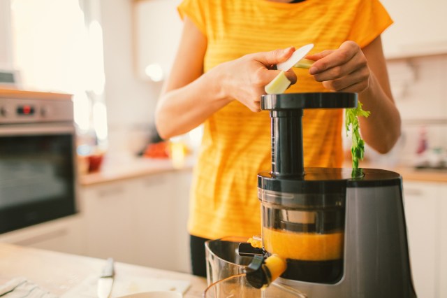 An image of a woman cutting a lemon into a juicer