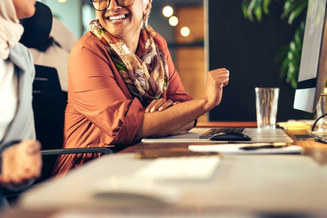 An image of a smiling woman sitting at a desk