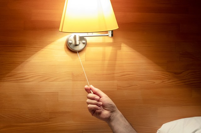 An image of a person pulling the string of a light sconce 