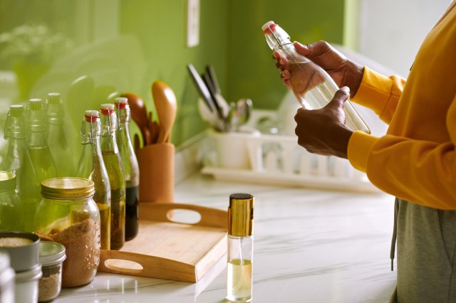 An image of a woman in a kitchen holding a clear bottle 