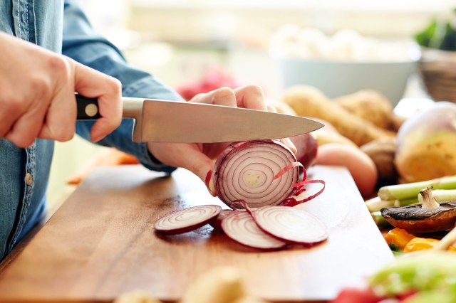 An image of a person cutting a red onion