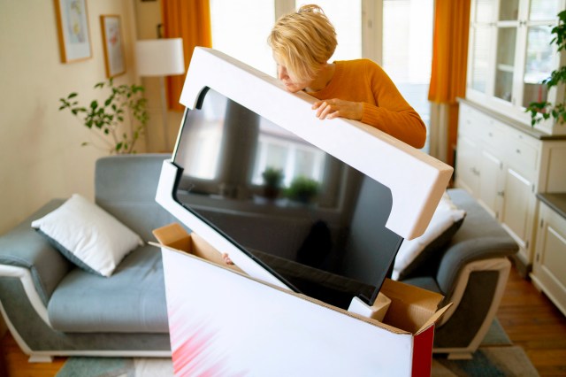 An image of a woman taking a TV out of a box