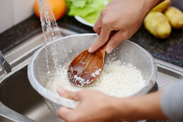 An image of rice in a colander under the running water