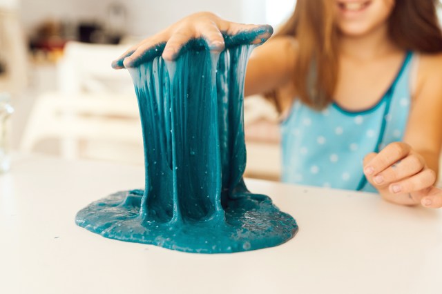 An image of a girl lifting her hand from a pile of blue slime