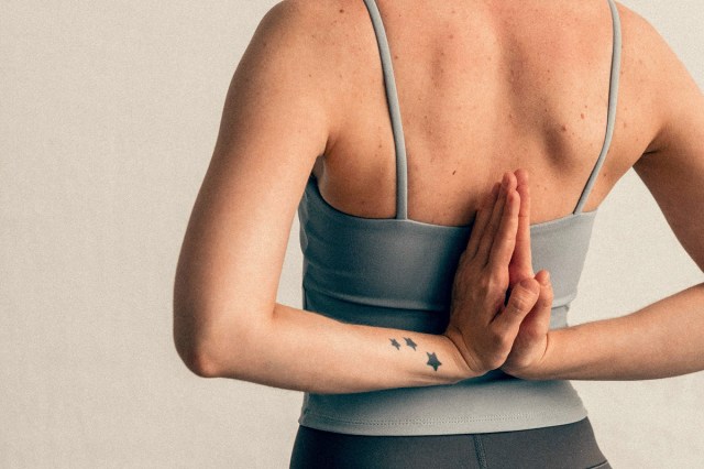 An image of a woman with her hands in prayer behind her back