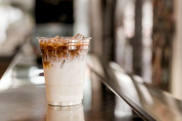 An image of a ice latte coffee in plastic glass on black table at cafe​