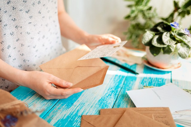 An image of a person putting an invitation into an envelope