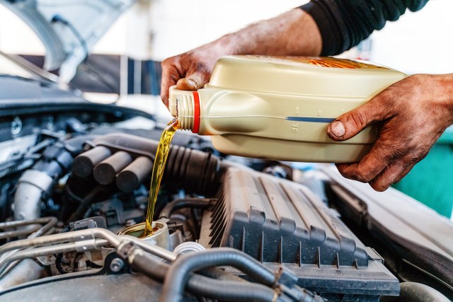 An image of a person pouring motor oil into a car engine
