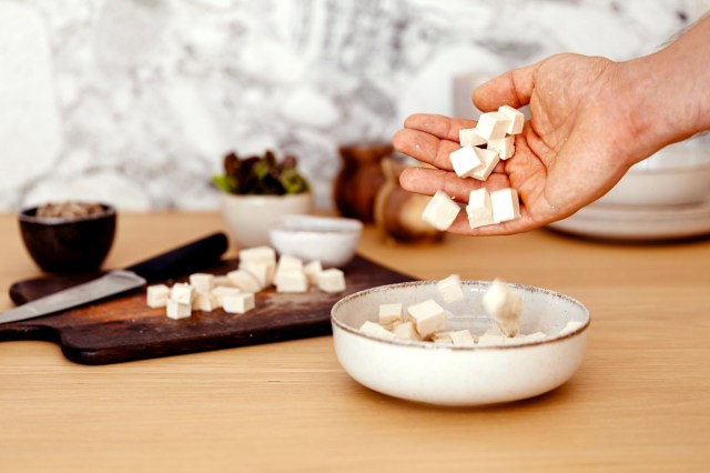 An image of a person putting cut tofu into a bowl