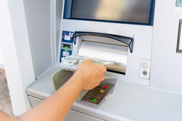 An image of a person taking money out of an ATM