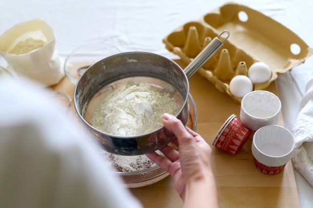 An image of a person sifting flour into a bowl