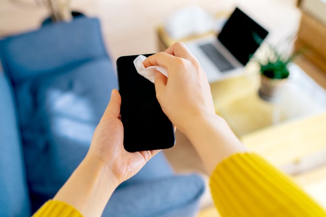 An image of a person wiping a phone screen with a wipe