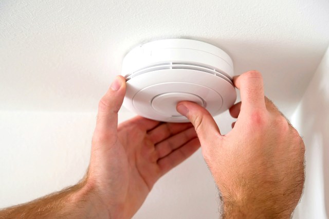 An image of two hands on a smoke detector