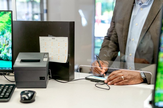An image of a person signing after making credit card payment