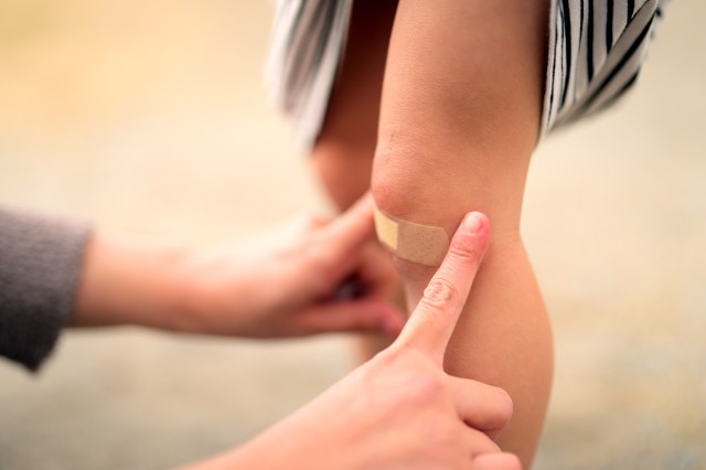 An image of a person putting a band aid on another person's knee
