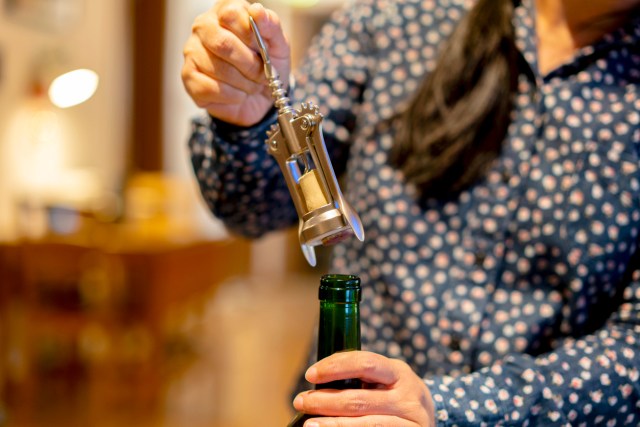 An image of a woman uncorking a bottle of wine