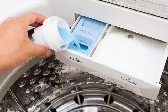 An image of a person pouring fabric softener into a washing machine