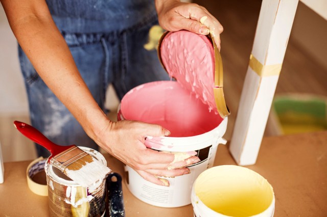 An image of a person opening a can of pink paint