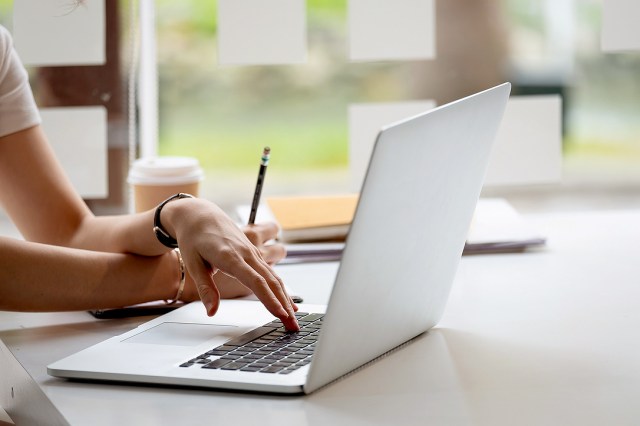 An image of a woman typing on a laptop
