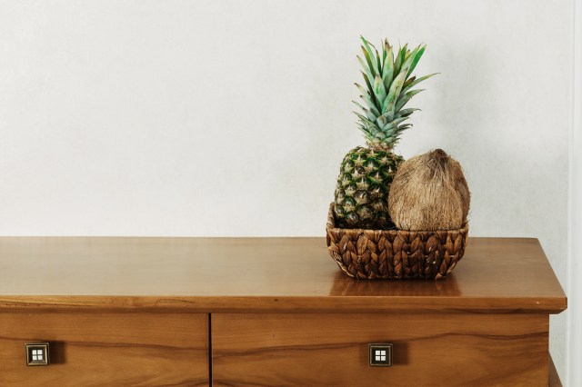 A bowl of fruit sits on a wooden dresser