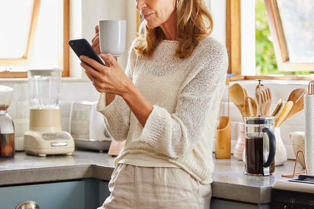 An image of a woman looking at her phone in a kitchen
