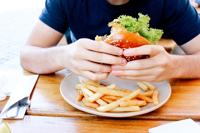 An image of a man eating a cheeseburger and fries