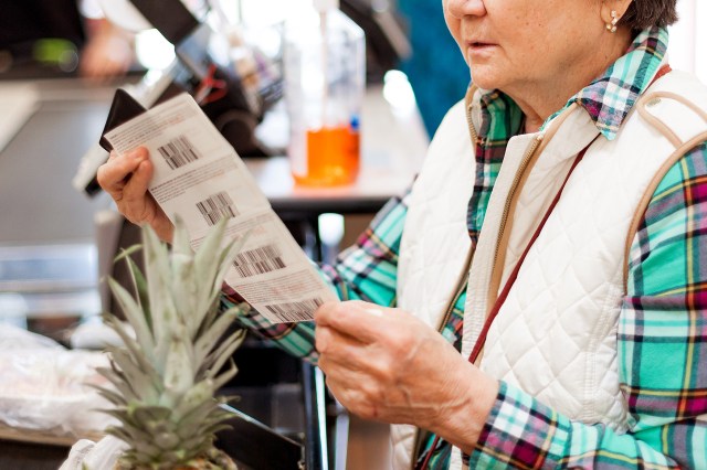 An image of a woman looking at a grocery store receipt