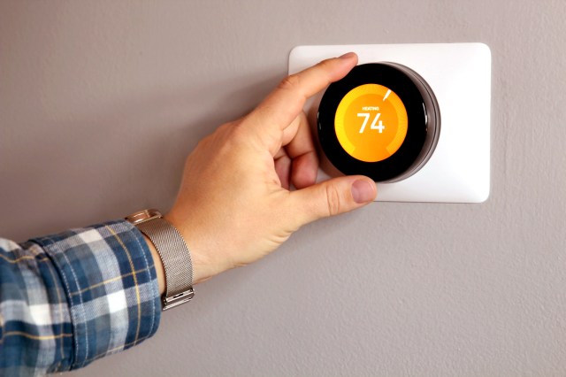 An image of a person adjusting a smart thermostat