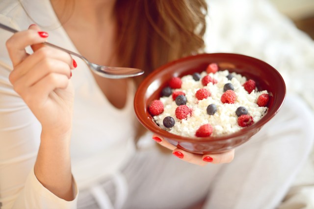 An image of a woman eating a bowl of cottage cheese with berries