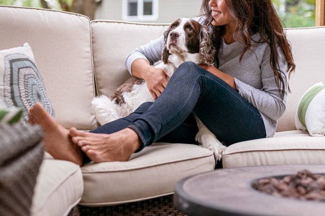 An image of a woman sitting on an outdoor couch with a dog