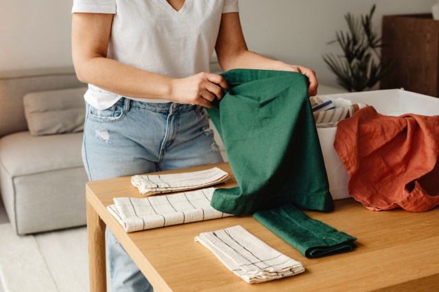 An image of a woman folding laundry on a table