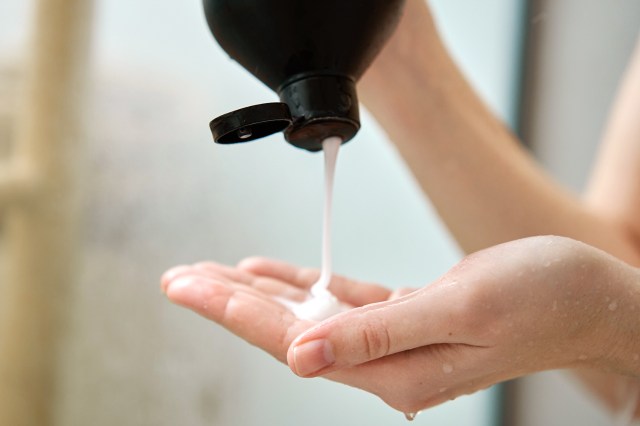 An image of a person squeezing conditioner into their palm